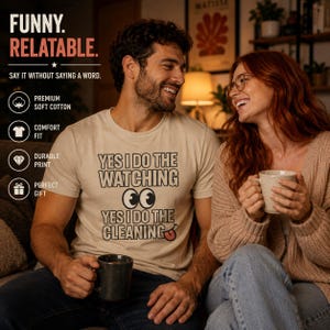 Può includere: Una t-shirt beige a maniche corte con testo nero che recita YES I DO THE WATCHING seguito da un'illustrazione di due occhi e dal testo YES I DO THE CLEANING con un piccolo grafico di una lingua rossa alla fine dell'ultima parola.