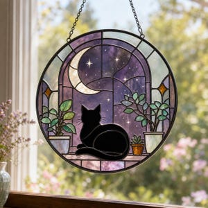 May include: A circular stained glass suncatcher featuring a black cat silhouette sitting on a ledge. The scene depicts a night sky with a crescent moon and stars visible through an arched window, flanked by potted green plants in glass containers.