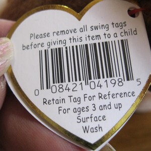 May include: A heart-shaped white swing tag with a gold border featuring a barcode and the text: Please remove all swing tags before giving this item to a child. Retain Tag For Reference. For ages 3 and up. Surface Wash. The tag has a small hole.