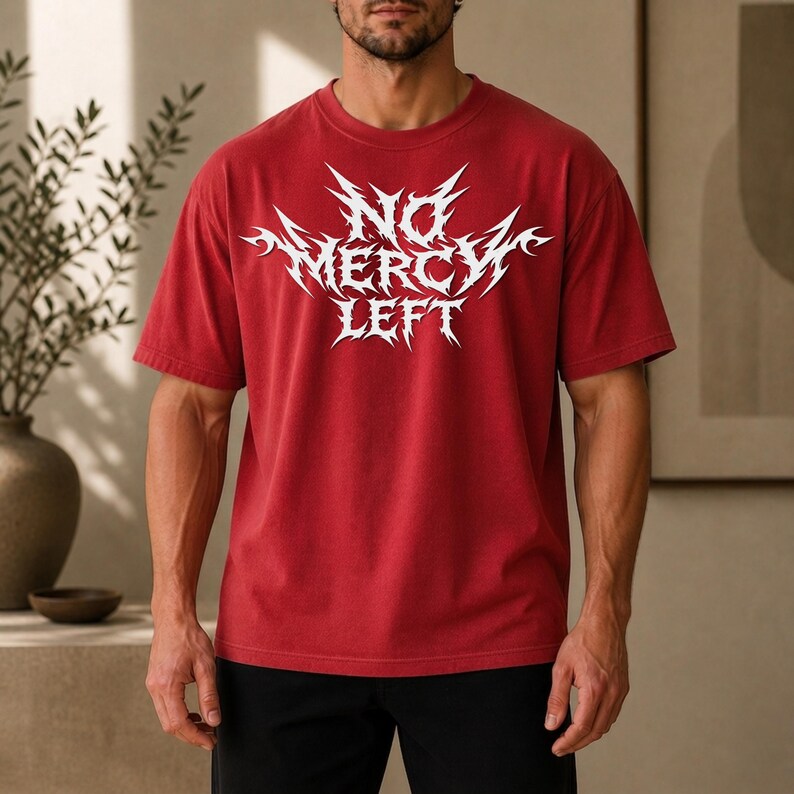 May include: A red short-sleeved t-shirt featuring a white graphic print on the chest with the text NO MERCY LEFT in a sharp, jagged, stylized font. The garment has a crew neckline and a relaxed fit, providing a solid color base for the design.