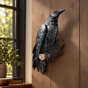 May include: A wall-mounted sculpture of a black raven perched on a textured brown branch. The bird features detailed feather patterns and a sharp beak, with the branch showing a circular wood grain end and rough bark texture on the surface.