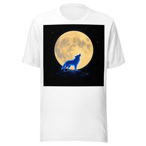 May include: A white short-sleeved t-shirt featuring a large square graphic on the chest. The graphic depicts a glowing blue wolf standing on a dark rocky outcrop, howling toward a large, bright yellow full moon set against a black night sky.