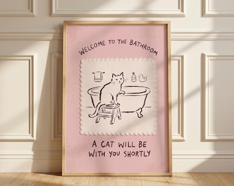 May include: A framed wall art print with a pink background featuring a dark brown line drawing of a cat sitting on a stool next to a bathtub. The text reads WELCOME TO THE BATHROOM and A CAT WILL BE WITH YOU SHORTLY in dark brown lettering.