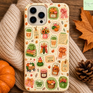May include: A cream-colored phone case featuring a repeating pattern of autumn-themed illustrations including pumpkins, coffee cups, books, scarves, and signs with text like Fall is my favorite, Pumpkin Patch, and Sweater Weather.