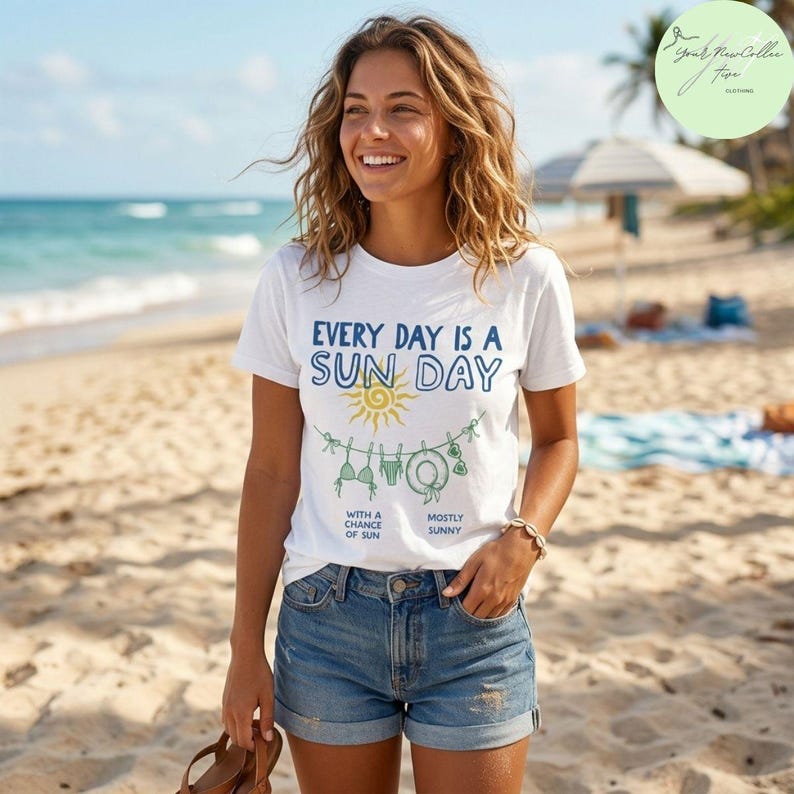 Peut inclure: Un t-shirt blanc &agrave; manches courtes avec le texte bleu "EVERY DAY IS A SUN DAY" au-dessus d'un soleil jaune et d'une illustration de corde &agrave; linge avec un bikini, un short, un chapeau de soleil et des lunettes, et le texte "WITH A CHANCE OF SUN" et "MOSTLY SUNNY".