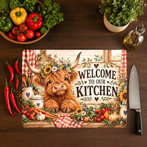 Peut inclure: Une planche à découper rectangulaire illustrée d'une vache Highland brune portant une couronne de fleurs, entourée de légumes et d'un tissu à carreaux rouges et blancs. Le texte Welcome to our kitchen est écrit en noir avec des cœurs.