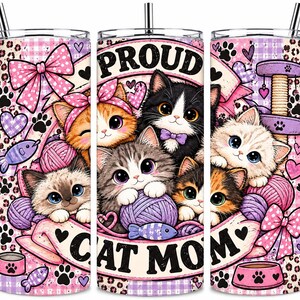 May include: A cylindrical tumbler with a metal straw featuring a pink and purple pattern of kittens, yarn balls, bows, and paw prints. The text PROUD CAT MOM is printed in black letters. The design includes illustrations of various cat breeds.