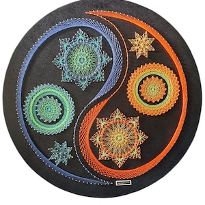 Puede incluir: Una pieza redonda de arte de hilo negro con un diseño de Yin y Yang. El lado Yin es azul y verde, mientras que el lado Yang es naranja y amarillo. El diseño incluye patrones de estrellas y círculos.