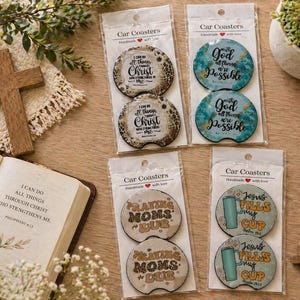 May include: An assortment of car coasters with inspirational quotes, including "I can do all things through Christ," and "With God all things are possible." The coasters are packaged in clear plastic and are displayed with a wooden cross, a Bible, and a rosary.