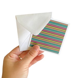 May include: A white envelope with a colorful striped card inside. The card has horizontal stripes in shades of green, yellow, pink, and red.