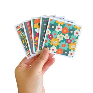 May include: A set of six colorful patterned cards with a floral design. The cards are green, orange, yellow, and red with white accents. The cards are arranged in a fan shape.