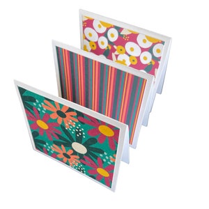 May include: Three blank greeting cards with white borders and colorful patterned designs. The designs include a green and orange floral pattern, a red and green striped pattern, and a pink and yellow floral pattern.