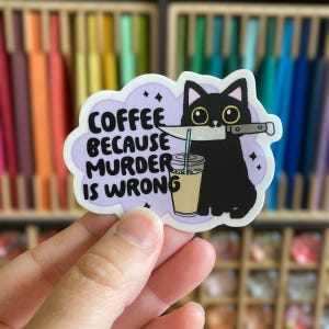 May include: A sticker featuring a black cat holding a knife in its mouth, with a coffee drink. The sticker has the text "Coffee Because Murder Is Wrong" in a purple cloud-shaped design. The background is a colorful array of pencils.