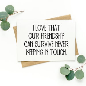 May include: A white card with black text that reads "I love that our friendship can survive never keeping in touch." The card is sitting on a brown envelope with green leaves on either side.