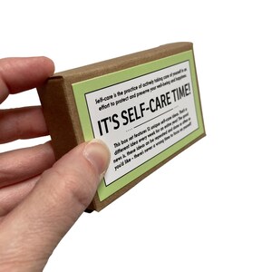 May include: A brown box with a green label that reads "IT'S SELF-CARE TIME!"  The label also includes the text "Self-care is the practice of actively taking care of yourself is an effort to protect and preserve your well-being and happiness."  This box set features 52 unique self-care ideas. That different idea every week for an entire year The good news is, these ideas can be repeated and done as often as you'd like - there's never a wrong time to focus on yourself.