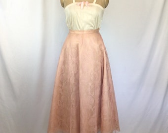 May include: A pink tulle skirt with a floral pattern. The skirt is full and flowing, and it is being displayed on a mannequin.