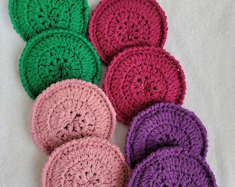 Puede incluir: Conjunto de ocho posavasos redondos de ganchillo en verde, rosa y morado. Los posavasos están hechos con un patrón de punto simple y tienen un centro ligeramente elevado.