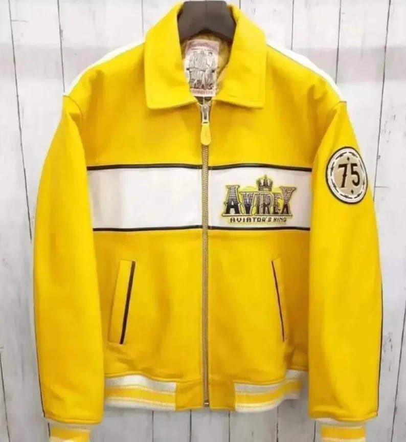 K&ouml;nnte beinhalten: Eine leuchtend gelbe Jacke mit einem wei&szlig;en horizontalen Bruststreifen und einem durchgehenden Rei&szlig;verschluss. Auf der Brust befindet sich ein gesticktes Avirex Aviator's King Logo mit Krone, am linken &Auml;rmel ein runder Aufn&auml;her mit der Zahl 75.