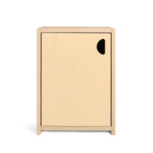 May include: A light-colored wooden cabinet with a single door and a rounded handle cutout. The cabinet has a simple, minimalist design with clean lines and a natural wood grain finish. The cabinet is rectangular and stands on a small base.