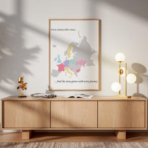 May include: A framed wall art print featuring a map of Europe with select countries highlighted in pastel colours. The text reads, "Every country tells a story..." at the top and "...And the story grows with every journey" at the bottom.
