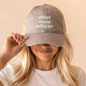 Op de afbeelding: Een grijze honkbalpet met een mesh achterkant en een gebogen klep. Het voorpaneel is voorzien van de wit geborduurde tekst "chief mom officer" in een strak, schreefloos lettertype. De pet heeft een gestructureerde kroon en een grijze knoop.