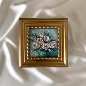 Könnte beinhalten: Ein kleines quadratisches Ölgemälde mit einem Blumenstrauß aus weißen und rosa Rosen in einer grünen Vase, gemalt mit dicken Impasto-Pinselstrichen. Das Kunstwerk befindet sich in einem verzierten, goldfarbenen Rahmen mit Perlenrand.