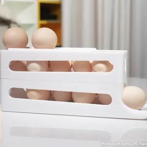 May include: A white plastic two-tiered egg dispenser rack holding multiple light brown eggs. The structure features horizontal cutouts on the sides for visibility and a sloped bottom tier for dispensing. Text at the bottom reads: Printed with SUNLU PC Filament.