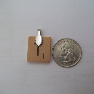 May include: A small wooden tile with the number "1" printed on it. The tile has a silver metal clasp attached to the top.