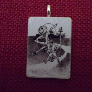 May include: A white ceramic pendant with a black and white illustration of a character from the movie "The Nightmare Before Christmas". The character is walking with a small child. The pendant has a silver bail.