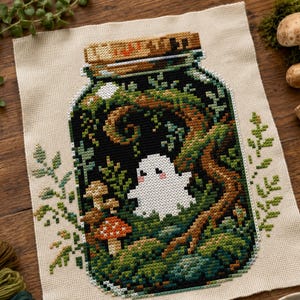 May include: A cross-stitch embroidery on beige fabric featuring a glass jar filled with a forest scene. Inside the jar, a small white ghost with pink cheeks sits among green moss, brown tree branches, and a red-capped mushroom with white spots.
