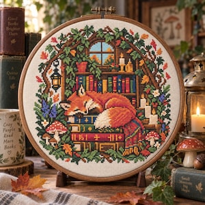 May include: A circular wooden embroidery hoop containing a cross-stitch pattern of a sleeping orange fox resting on a stack of colourful books. The scene includes a window, bookshelves, glowing candles, a hanging lantern, and red-capped mushrooms.