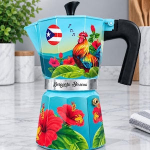 May include: A light blue stovetop espresso maker featuring a colorful rooster, red hibiscus flowers, green leaves, and the Puerto Rican flag. The text Despierta Boricua is printed on the silver band. It has a black handle and a black lid knob.