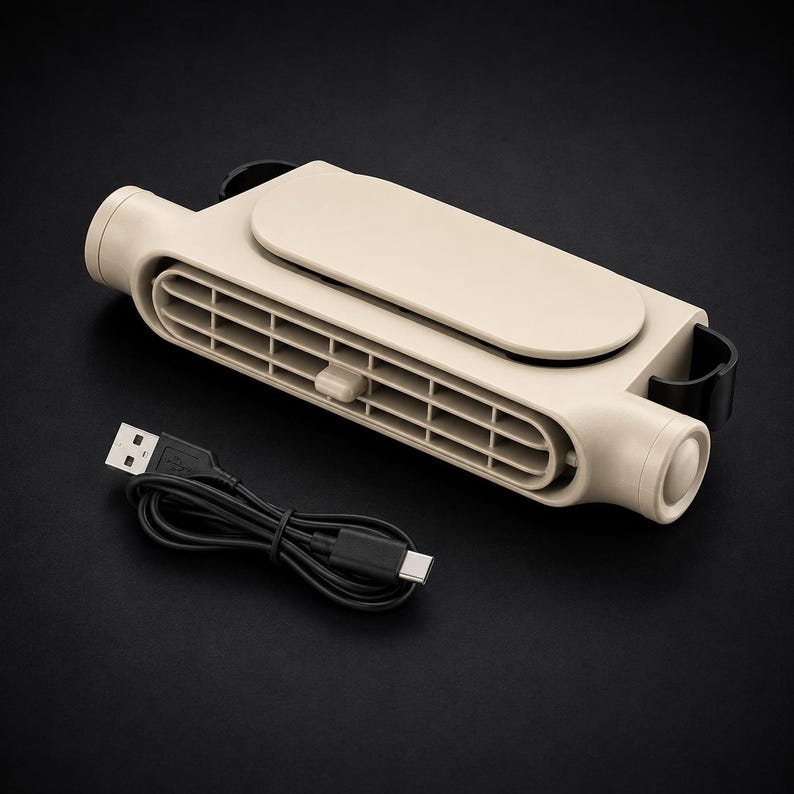 Puede incluir: Un ventilador de cuello port&aacute;til de color beige con una rejilla de ventilaci&oacute;n horizontal, un panel superior s&oacute;lido y clips laterales negros. El dispositivo cuenta con una peque&ntilde;a pesta&ntilde;a de ajuste en la rejilla frontal y un cable de carga USB-A a USB-C.