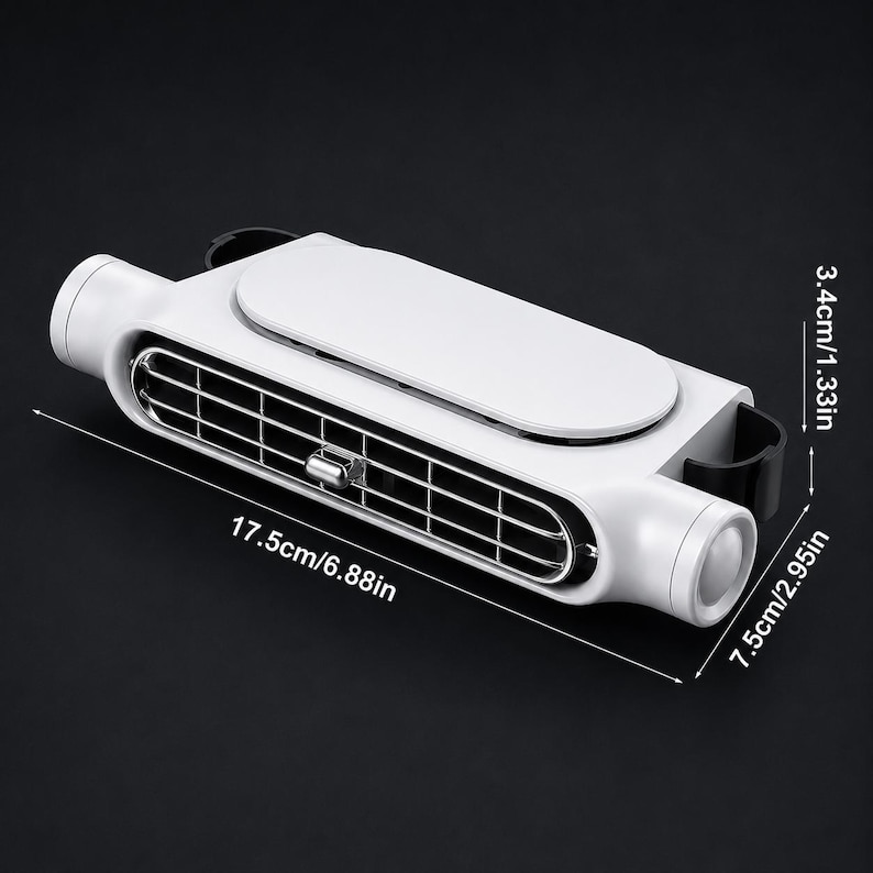 Puede incluir: Un ventilador de ventilaci&oacute;n port&aacute;til blanco y negro con una rejilla rectangular y un panel superior liso. El dispositivo mide 17,5 cm de largo, 7,5 cm de ancho y 3,4 cm de alto, con una perilla de ajuste central de color plateado.