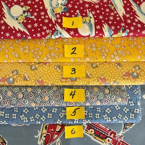 May include: Six stacked fabric swatches labeled with yellow numbered tags. The top fabric is red with winter scenes, followed by yellow floral, yellow polka dot with figures, white with circular patterns, blue floral, and blue with red toy cars.