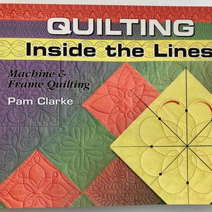 May include: A softcover instructional book titled Quilting Inside the Lines: Machine & Frame Quilting by Pam Clarke. The cover features a colorful patchwork quilt design with various stitched patterns and a yellow diamond diagram with arrows.