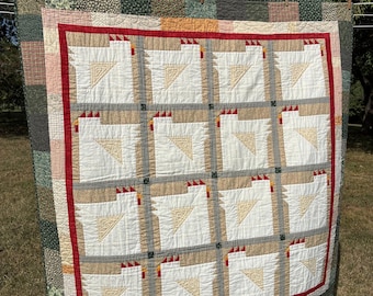 May include: A quilt featuring a grid of twelve white chicken blocks with red combs and tan wings. The blocks are separated by black and white checkered sashing and framed by a solid red border, surrounded by a multi-colored patchwork outer border.
