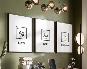 May include: A home office with a wooden desk, a green office chair, and three framed prints on the wall. The prints feature the chemical symbols for silver, gold, and platinum.