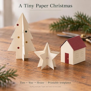 Könnte beinhalten: Ein Bastelset mit dem Titel A Tiny Paper Christmas, bestehend aus einem cremefarbenen Baum mit kleinen bunten Punkten, einem Stern mit dem Text JOY und einem Haus mit rotem Dach und Tür. Enthält druckbare Vorlagen für Baum, Stern und Haus.