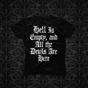 Puede incluir: Una camiseta negra de manga corta con el texto blanco "Hell Is Empty, and All the Devils Are Here" impreso en una fuente gótica estilizada en el centro del pecho. La prenda tiene un cuello redondo y un corte estándar.