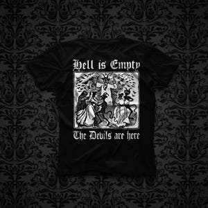 May include: A black short-sleeved t-shirt featuring a white graphic print of a horned figure surrounded by dancing people and bats. The text "Hell is Empty" appears above the illustration, and "The Devils are here" is printed below the image.