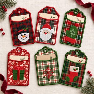 May include: Six rectangular fabric gift tags with rounded tops and eyelets. Designs include a snowman, Santa Claus, a green mitten, a green gift box, a red snowflake, and a red stocking, all set against red and green plaid or patterned fabric.