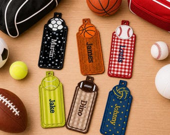May include: Six rectangular luggage tags featuring sports ball motifs at the top. The tags are black with stars, orange with a basketball texture, red gingham, lime green stripes, tan plaid, and blue with stars, personalised with names in embroidery.