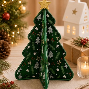 Könnte beinhalten: Eine dreidimensionale Weihnachtsbaumdekoration aus Stoff in Dunkelgrün mit einem wiederkehrenden Muster aus weißen Sternen, stilisierten weißen Baumumrissen, grünen Tannennadeln und kleinen roten Beeren. An der Spitze befindet sich ein goldener Stern.