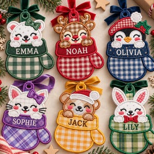 Puede incluir: Seis adornos navideños bordados con forma de manopla, cada uno con un animal diferente: un oso, un reno, un pingüino, un gato, un osito de peluche y un conejo. Cada adorno está personalizado con un nombre y rematado con una cinta a juego.