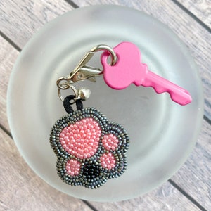May include: Pink and grey beaded paw print keyring with a pink plastic key attached.