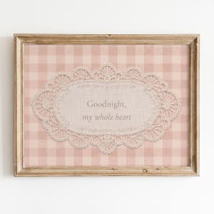 May include: A rectangular framed wall art piece featuring a light pink and white gingham background. Centered is an oval-shaped white lace doily graphic with the text Goodnight, my whole heart printed in a soft gray serif font.