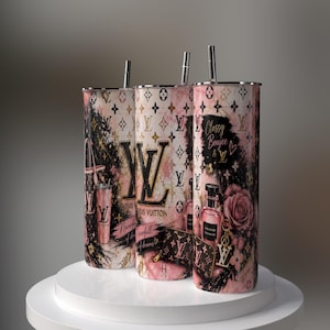 Può includere: Tre bicchieri cilindrici con cannuccia, caratterizzati da un motivo marmorizzato rosa e nero, loghi LV dorati e accenti floreali. I design includono illustrazioni di borse, flaconi di profumo e il testo "Classy Boujee & LV" e "Neverfull of dreams."