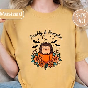 Mustard shirt with a cute hedgehog in a pumpkin and "Prickly & Pumpkin" text.