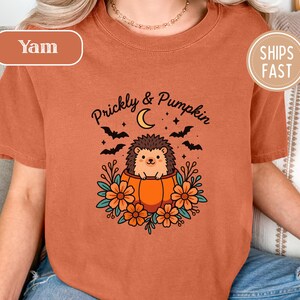 Orange shirt with "Prickly & Pumpkin" text, hedgehog, moon, bats, and flowers.